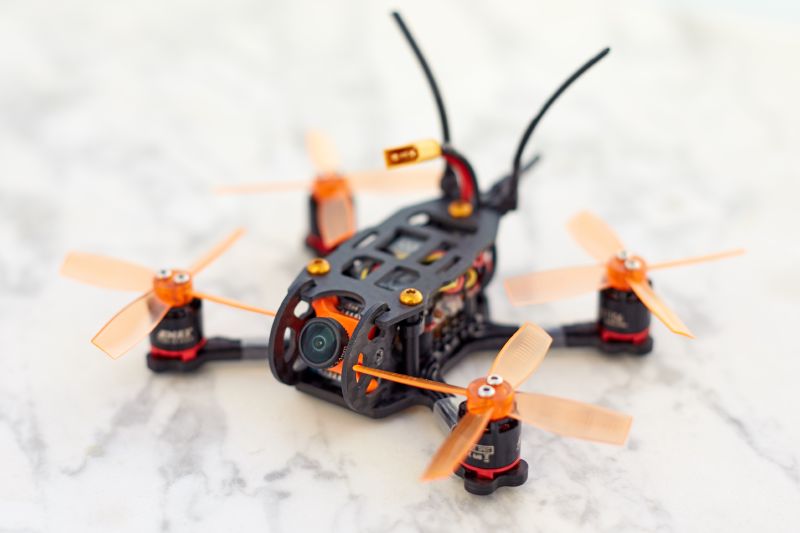 A custom-made first-person view (FPV) freestyle drone made of carbon fibre with orange propellers and a camera
