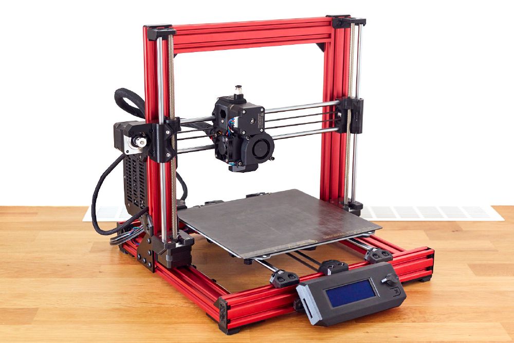 A Prusa Bear Upgrade 2.1 3D printer with red aluminum extrusions and black printed parts